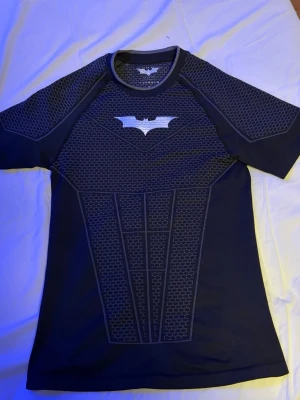 Svart YoungLa Batman compression shirt  - Säljer en svart YoungLa compression shirt med Batman-logga på bröstet och ett coolt mönster.  Tröjan är extremt limiterad och såldes slut på mindre än 1 minut! Enbart testad - Allt og är inkluderat. 