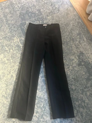 Svarta kostymbyxor från Nelly - Säljer ett par klassiska svarta kostymbyxor från Nelly. Byxorna har raka ben. 