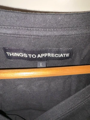 Svart t-shirt Things To Appreciate - Cool svart t-shirt från Things To Appreciate med vit tryckt text i Metallica-inspirerad stil på bröstet. Klassisk rund hals och korta ärmar. Tillverkad i mjuk bomull som känns skön mot huden. Perfekt för dig som gillar streetwear och statement-plagg.