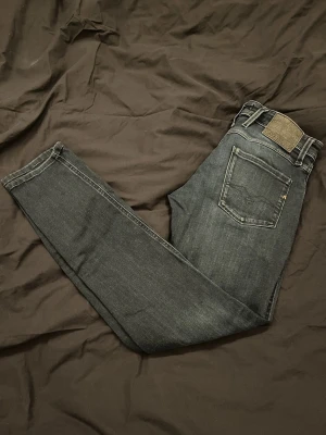 Replay anbass - Snygga mörkblå jeans från replay med klassisk femficksdesign och raka ben. Jeansen har subtila slitningar och kontrastsömmar, samt en ikonisk läderpatch bak i midjan. Perfekta för en avslappnad och stilren look. I storlek W30/L32