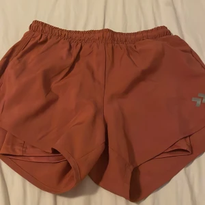 Rostbruna träningsshorts från Lager157 - Snygga rostbruna träningsshorts från Lager157  med elastisk midja och diskret logga på ena benet. Lätta och luftiga, perfekta för gymmet eller löprundan. Klassisk sportig design med innerbyxa för extra komfort.