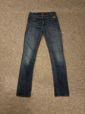 Blå raka jeans från Nudie Jeans - Säljer ett par klassiska blå jeans från Nudie Jeans med raka ben och fem fickor. Jeansen har en snygg tvättad look och detaljerade sömmar på bakfickan. Tillverkade i bomull med en bekväm passform som funkar till det mesta.