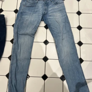 Ljusblå skinny jeans - Säljer ett par ljusblå skinny jeans med klassisk femficksdesign och snygga sömdetaljer på bakfickorna. Jeansen har normal midja och är tillverkade i ett stretchigt denimtyg som sitter tajt längs benen. Perfekta för en avslappnad och trendig look.