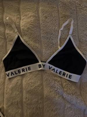 Svart och vit bralette från By Valerie - Stilren svart bralette från By Valerie med vita kanter och justerbara axelband.  Använd på plåtning.