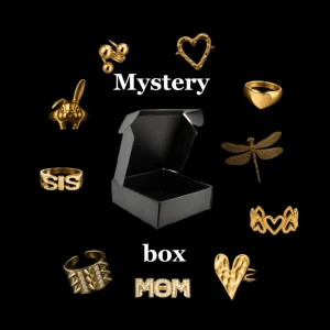 Mystery box guld  - Mystery box fylld med unika guldfärgade ringar i olika former, som hjärta, kanin med rosa sten, drakflyg, vampyrtänder, masker och text som SIS och MOM. Perfekt för dig som gillar att överraska dig själv med snygga accessoarer. (Obs endast 1 Pär box, vid beställning av bundle får man alltid 2 olika!)
