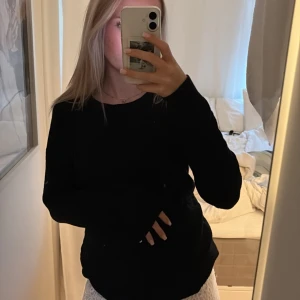 Svart långärmad tröja från Vila - En svart långärmad tröja från Vila i enkel och stilren design. Tröjan har rund halsringning och normal passform, perfekt att matcha med jeans eller kjol. Mjuk och skön, passar året runt.