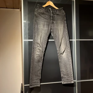 Svarta jeans   - Svarta jeans med tvättad look från Jack and Jones , loose fit-modell med raka ben och klassiska fem fickor. Jeansen har bälteshällor, knapp- och dragkedjegylf samt broderad text på insidan av linningen. Perfekta för en avslappnad stil.