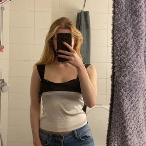 Svartvit topp med knytband -  svartvit topp med breda svarta axelband och knytband i ryggen. 