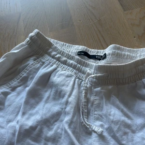 Vita linnebyxor med dragsko - Snygga och luftiga vita linnebyxor från 157 med elastisk midja och dragsko. Perfekta för varma dagar, med avslappnad passform och sidfickor. Byxorna har en rak siluett och är tillverkade i mjukt linnematerial.