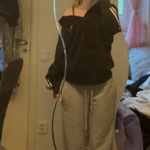 Svart Adidas tröja med dragkedja - Svart tröja från Adidas. Tröjan har hög krage med dragkedja på halva tröjan och en loose passform. Kan användas på olika sätt. Perfekt för en chill och sportig stil.