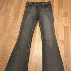 Svarta bootcut jeans med rå kant - Snygga svarta jeans med bootcut-modell och rå, fransad kant nertill. Jeansen har klassisk femficksdesign och dragkedja. Materialet är jeans och färgen är tvättad svart med lätt slitning för en cool look. Har inte spilt något på dem, byxorna ska vara så!!