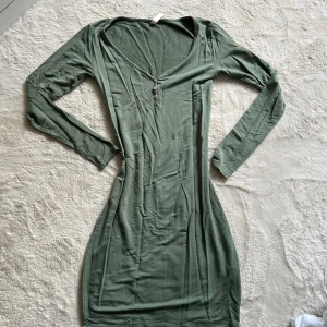 Grön långärmad nattkläning Hunkemöller  - Snygg grön långärmad klänning i figurnära modell med v-ringning och knappar framtill. Mjuk och stretchig känsla, perfekt för dig som gillar enkel men stilren design.