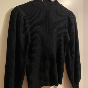 Svart stickad tröja med halvpolo och puffärmar! XS - Nyskick!  Ribbad stickad svart tröja från Only!  Supersnygga ärm-muddar!  Endast använd 1 gång!   Den har en hög halsringning och långa ballongärmar! Snygga ribbade ärmsluten! sofistikerad touch. Är nyligen inköpt av mig, så den säljs för 399kr på hemsidan!  Se sista bilderna hur jag mätt.   Den är stretchig   Highneck Pullover