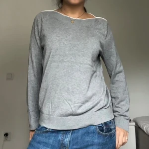 Grå tröja från Esprit med vit kant vid halsen - Enkel och stilren grå tröja med lång ärm och vit kant längs den breda halsringningen. Tröjan har ribbademm muddar vid ärmslut och nederkant.
