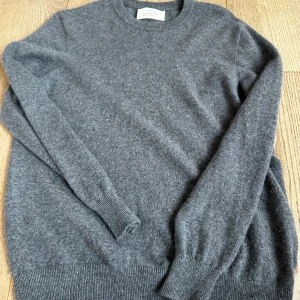 Mörkgrå stickad tröja från Zara Origins kashmir  - Mysig mörkgrå stickad tröja från Zara Origins i storlek S. Klassisk rund halsringning och ribbade muddar vid ärmslut och nederkant. Perfekt för lager-på-lager och enkel att matcha med jeans eller kjol.