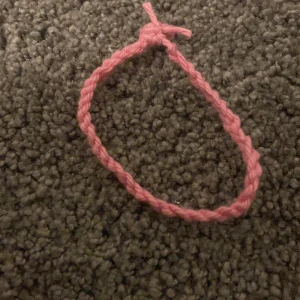 Rosa flätat armband  - Säljer ett enkelt och snyggt rosa armband.  Perfekt för dig som gillar handgjorda accessoarer och vill ha en färgklick på handleden.