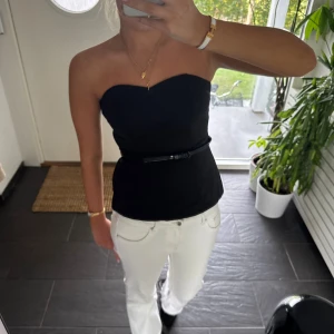 Svart tubtopp/Festtopp med bälte  - Snygg svart tubtopp med smalt bälte i midjan. Toppen är axelbandslös och har en stilren, figurnära passform. Skärpet har några små defekter men det är inget som syns 🤗