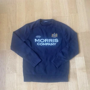 Marinblå stickad tröja Morris Company - Snygg marinblå stickad tröja från Morris Company med broderad logga och emblem på bröstet.  Pris kan diskuteras 
