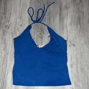 ”Triangle singlet top”  - Snygg blå halterneck topp från Gina Tricot i storlek XS. Toppen har knyt i nacken, djup v-ringning. Gjord i mjukt och stretchigt material för en bekväm passform. Aldrig använd endast testad.