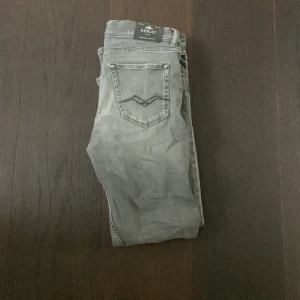 Replay grå jeans  - Snygga grå jeans från Replay med klassisk femficksdesign och cool detaljsöm på bakfickan. Jeansen har en avslappnad passform och är tillverkade i mjukt jeanstyg som ger en skön känsla. Perfekta för dig som gillar en stilren och enkel look.