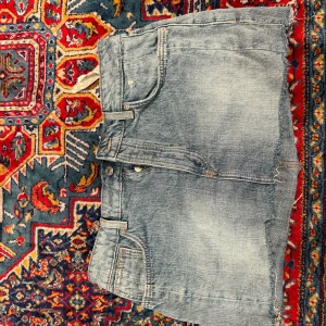Blå jeanskjol från Zara - Säljer en snygg blå jeanskjol från Zara i klassisk femficksmodell. Kjolen är kort med råa kanter nertill och har en avslappnad vibe. Perfekt för dig som gillar denim och vill ha en enkel men trendig look.
