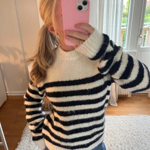 Randig stickad tröja  - Supermysig stickad tröja med breda svarta och vita ränder. Tröjan har rund halsringning, långa ärmar och en lite fluffig känsla. Perfekt för kyliga dagar och enkel att styla med jeans eller kjol.