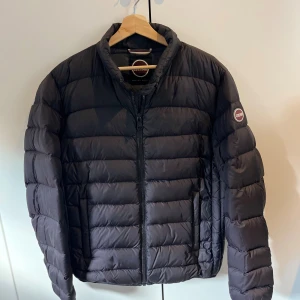 Svart pufferjacka från Colmar - Säljer en svart pufferjacka från Colmar Originals i storlek 52. Jackan har quiltad design, dragkedja framtill och två fickor. Klassisk rund Colmar-logga på ärmen. Perfekt för kalla dagar och riktigt snygg till streetwear-stilen.