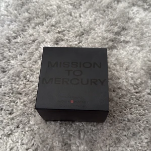 Omega x Swatch MoonSwatch Mercury - Säljer en Omega x Swatch MoonSwatch Mission to Mercury. Klockan har svart urtavla med vita detaljer och grått band. Boetten är i biokeramik och designen är inspirerad av Omega Speedmaster. Kommer med originalbox, manual.använd Max 5 gånger