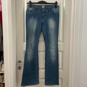 Blå bootcut jeans Twist & Tango - Snygga blå jeans från Twist & Tango i klassisk bootcut-modell. Jeansen har en medelhög midja, fem fickor och coola slitningar framtill. Perfekta för dig som gillar en retroinspirerad look med utsvängda ben. Materialet är klassisk denim.