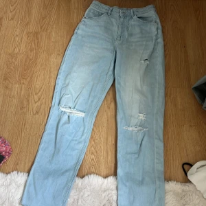 Ljusblå ripped jeans straight fit - Snygga ljusblå jeans med raka ben och slitna detaljer vid knäna. Klassisk femficksmodell med normal passform och hög midja. Perfekta för en avslappnad och trendig look.