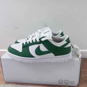 Nike Dunk Low vit/grön strl 38 - Egedesignade Nike Dunk Low oanvända. Säljer pga för liten storlek. Nypris: 1749kr