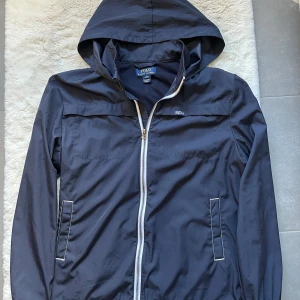Ralph Lauren windbreaker - Snygg marinblå vindjacka från Polo Ralph Lauren. Skick 9/10 inga defketer eller nått. Perfekt för blåsigt och regnigt väder. Det är L i barn storlek sp alltså strl 164. 