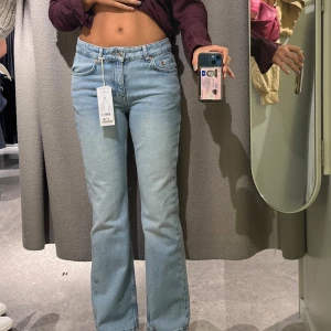 Ljusblå raka jeans med låg/medelhög  - Säljer ett par ljusblå jeans med klassisk femficksdesign och medelhög midja. Jeansen har raka ben och är tillverkade i mjukt denimtyg. Perfekta för en avslappnad och trendig look.