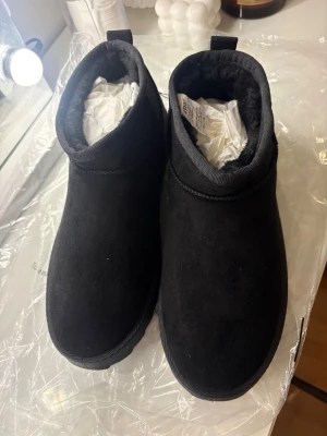 Svarta uggs från CRW i mocka - Mysiga svarta vattentäta Uggs från CRW. Utsidan är i mjuk mocka och insidan är fodrad med fluffigt material för extra komfort. Perfekta för att hålla fötterna varma hemma, ute eller i stallet under kyliga dagar. Helt oanvända, säljes då de är för små för mig.✨💞
