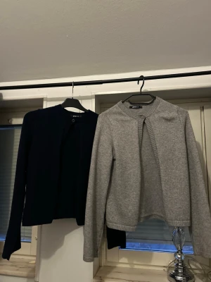 Två enkla koftor från Gina Tricot - Säljer två stilrena koftor från Gina Tricot, en i mörkblått och en i ljusgrått. Båda har rund halsringning, knapp framtill och långa ärmar. Perfekta att slänga över en t-shirt eller linne för en clean look.