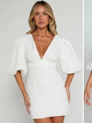 Vit kort klänning med puffärmar - Säljer min studentklänning! Superfin vit kort klänning med djup v-ringning och stora puffärmar. Klänningen har en markerad midja och struktur i tyget!