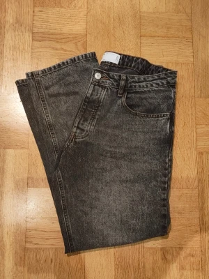 Svarta straight jeans från ASOS Design - Snygga svarta jeans från ASOS Design i tvättad look. Modellen har raka ben, klassisk femficksdesign och hög midja. Jeansen är gjorda i kraftig bomullsdenim och har silverfärgad knapp och dragkedja. Perfekta till en avslappnad streetstyle. Längd 32! W33/L32.