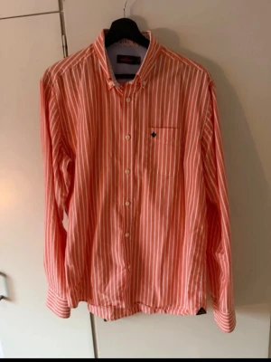  randig skjorta från Morris - Säljer en snygg  randig skjorta från Morris . Skjortan har klassisk krage, bröstficka med liten logga och vita knappar framtill. Perfekt för dig som gillar en stilren och fräsch look.