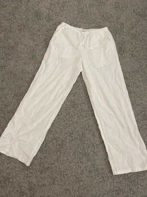 Vita linnebyxor med resårmidja - Snygga och luftiga vita linnebyxor med rak passform och resår i midjan. Perfekta för varma dagar och ger en chill vibe till din outfit. Byxorna har en enkel design utan synliga detaljer och är tillverkade i mjukt linnematerial.