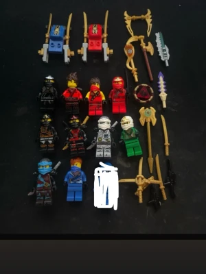 Lego Ninjago figurer och vapen - Samling med Lego Ninjago minifigurer i olika färger som svart, röd, vit, grön och blå. Medföljer flera tillbehör som svärd, spjut, sköldar och två små fordon i blått och rött. Perfekt för dig som gillar Ninjago och vill bygga egna äventyr.