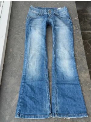 Blå bootcut jeans Vero Moda - Snygga blå bootcut jeans med slitningar och dubbla knappar i midjan från Vero Moda.❤️Midjemått tvärs över 38 cm,  midjehöjd: 18 cm, innerbenslängd: 79 cm🩷
