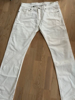 Vita raka jeans från replay - Säljer ett par klassiska vita replay jeans med rak passform. Jeansen har fem fickor, knappgylf och är tillverkade i kraftig bomullsdenim. Perfekta för dig som vill ha en clean och tidlös look.
