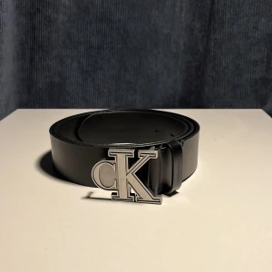 Svart läderbälte från Calvin Klein - Snyggt svart bälte i äkta läder från Calvin klein. Tillverkat i 100% kohud och har en exklusiv känsla. Bältet passar till alla olika byxor.💯