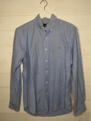 Ralph Lauren Skjorta - Klassisk ljusblå skjorta från Polo Ralph Lauren. Säljes i mycket fint skick. Storlek M. Hör av er vid eventuella frågor! 😊