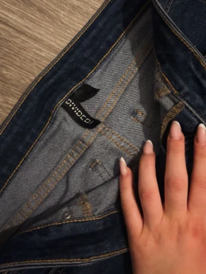 Mörkblå jeans från Divided - Snygga mörkblå jeans från Divided med klassisk femficksdesign och kontrastsömmar. Jeansen har en smal passform och är perfekta för dig som gillar en stilren look. Materialet är mjukt och stretchigt för extra komfort.