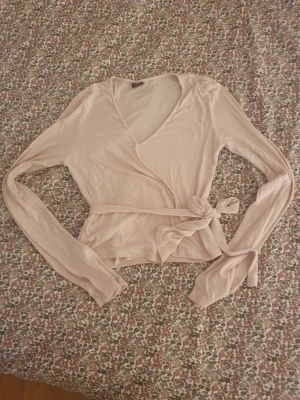 Ljusrosa omlottopp med knytband - Jättegullig ljusrosa omlottopp i storlek S med långa ärmar och knytband i midjan, En perfekt lite svalare tröja❣️ 