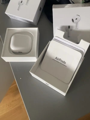 Apple AirPods 4 med laddningsetui - Säljer ett par vita Apple AirPods gen 4 med aktiv brusreducering och trådlöst laddningsetui. Snygg och kompakt design i blank plast, perfekt för musik, poddar och samtal. Levereras i originalförpackning med tillbehör.