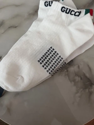 Vita ankelsockor  -  Klassisk design med ribbad kant och en liten röd och grön rand på hälen. Perfekta för sneakers och vardagsstil.