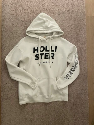 Vit Snygg Hoodie Från Hollister🤩Storlek S - 🤍 Vit Hollister hoodie – Dam, Strl S 🤍  Snygg och bekväm hoodie från Hollister i klassiskt vitt ⚪️ Perfekt för vardag, skola eller mysiga dagar hemma. Mjuk och skön i materialet!  📏 Mått: • Armlängd: 56 cm • Axelbredd: 52 cm • Längd: 59 cm  👕 Passform: Normal/avslappnad ✨ Skick: Mycket Bra Skick ✅🤗