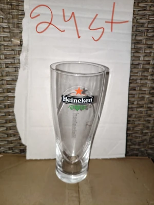 Heineken ölglas i klarglas - Säljer ett stilrent ölglas från Heineken i transparent glas. Glaset har en klassisk avsmalnande form och Heineken-loggan med den röda stjärnan tryckt på framsidan. Perfekt för dig som gillar att samla på ölglas eller vill ha något extra till hemmabaren.
